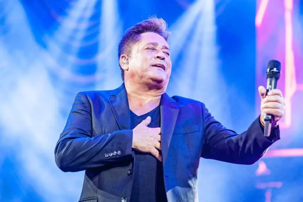 Cantor Leonardo sorrindo no palco durante um show da turnê Uma História Sem Fim em 2026, com luzes coloridas ao fundo.