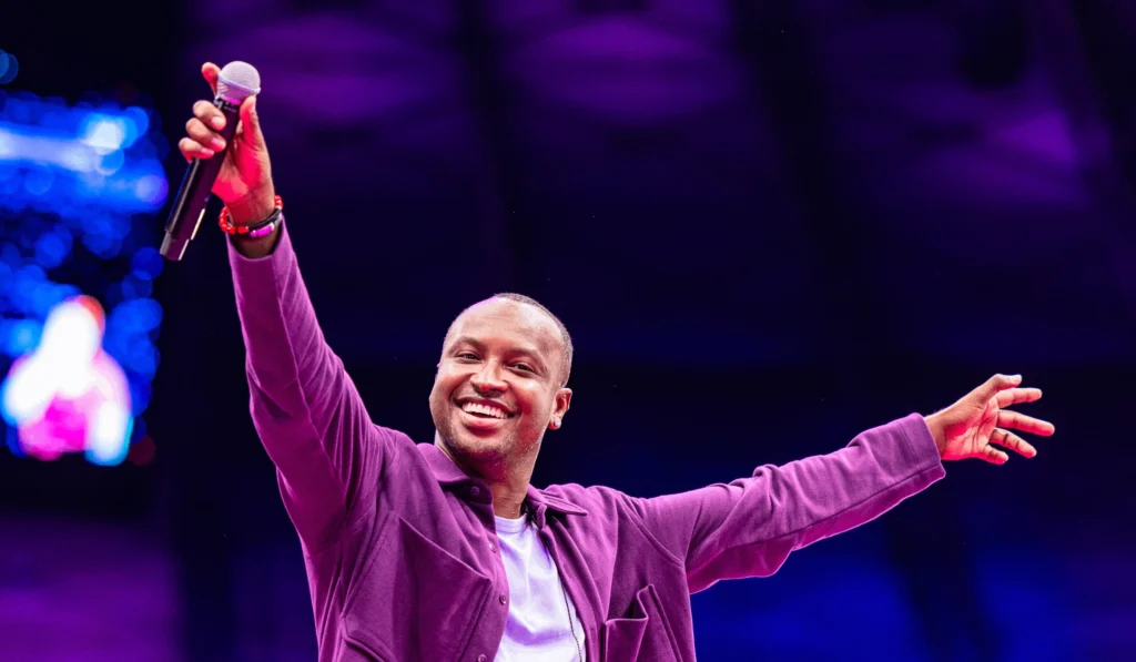 Thiaguinho cantando no palco durante a estreia da turnê "Bem Black" em 2026, com iluminação cênica e plateia vibrante.