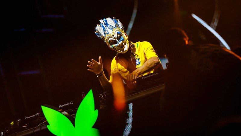 Boris Brejcha se apresenta no Greenvalley, Brasil, com sua máscara veneziana e uma multidão animada ao fundo.