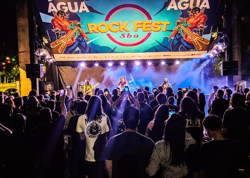 Público em um festival de rock com palco e iluminação colorida